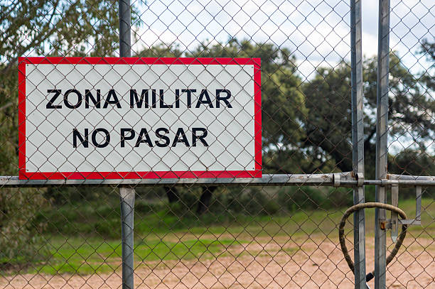 istock Wire fence to control restricted access, with a sign that reads: Military Zone  No Entry. 2207128039