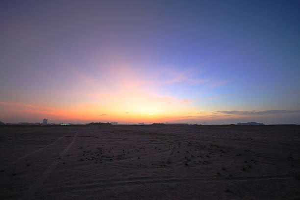 Sunrise over flat sand desert view at the horizon.