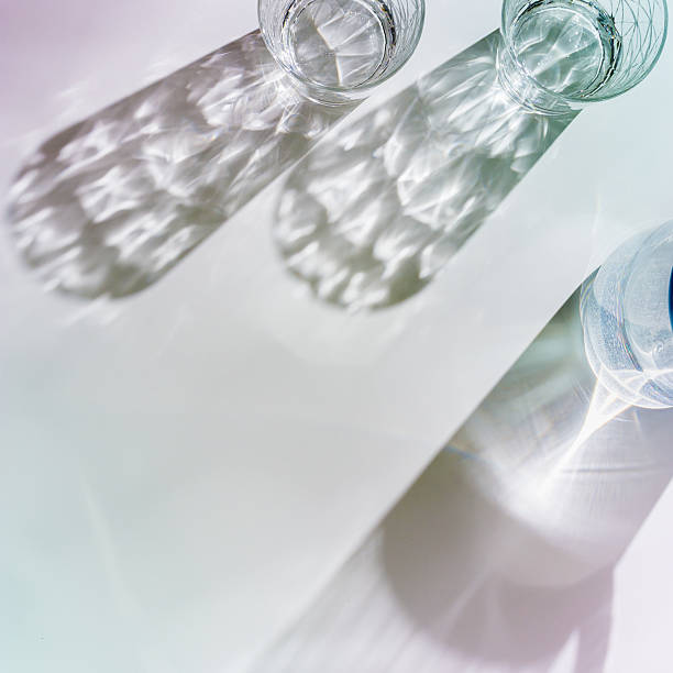istock Water Glasses and water jug with Shadows and sunlight Reflection on white background, colored photo minimal style, aesthetic summer still life, refraction throug crystal shine cups, caustics 2207131245