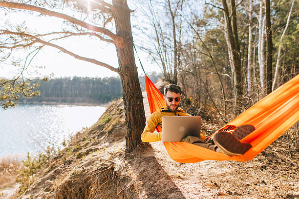 istock Handsome Man Working Remotely on Laptop in Hammock Amidst Nature 2207132170