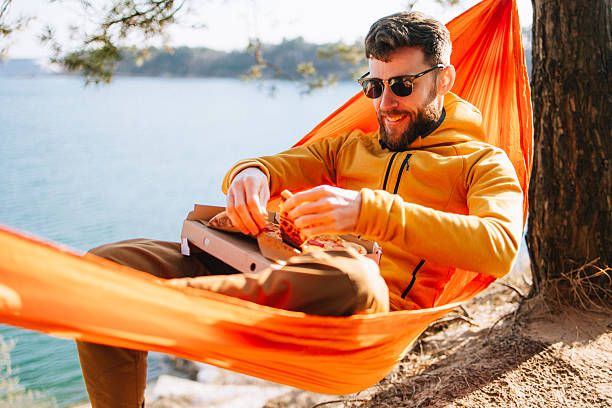 istock Man Celebrates Perfect Spring Day with Pizza in Hammock 2207132402