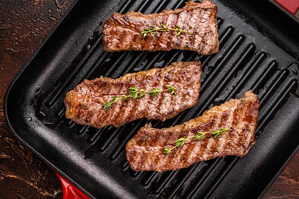 istock Grilled Tri tip steaks, marbled beef meat on pan with herbs. brown background. top view 2207139446