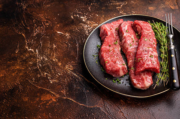 istock Tri tip steaks, Raw marbled beef meat on plate with herbs. brown background. top view 2207139450