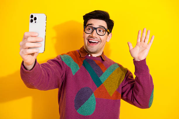 istock Cheerful Young Man Taking a Selfie on Yellow Backdrop Wears Colorful Sweater 2207140204