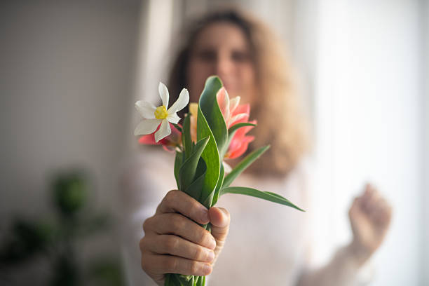 Photo of optimistic blond curly hairdo lady hold present flowers wear top isolated on pastel pink color background