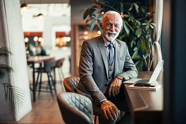 istock Senior Businessman Smiling While Working on Laptop in Modern Cafe Setting 2207143871