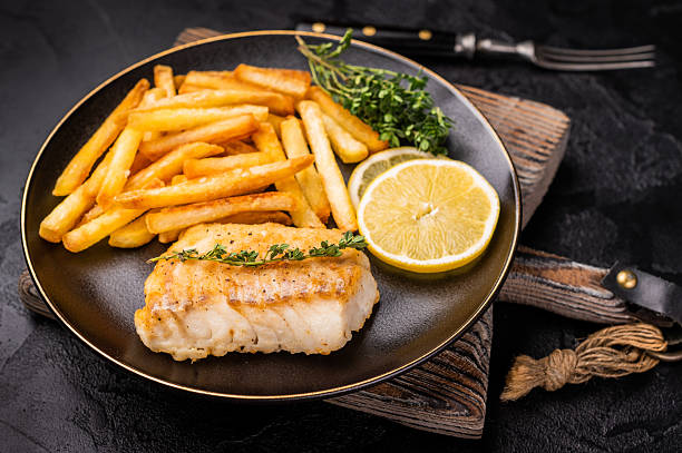 istock Homemade Fish and chips with roast cod whitefish fillet and fried potatoes on plate. black background. top view 2207145403
