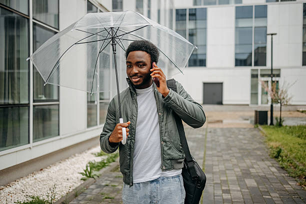 istock Man going to work walking outside on rainy day while talking on mobile phone 2207145432