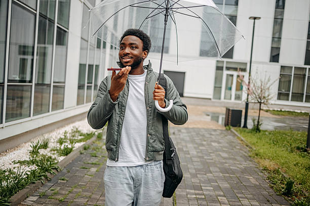 istock Man going to work walking outside on rainy day while talking on mobile phone 2207145436