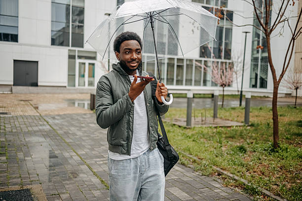 istock Man going to work walking outside on rainy day while talking on mobile phone 2207145437