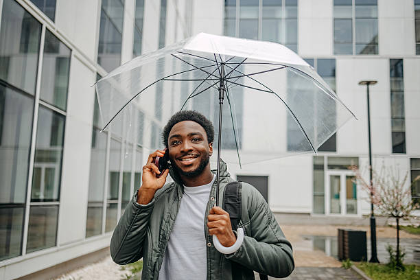 istock Man going to work walking outside on rainy day while talking on mobile phone 2207145439