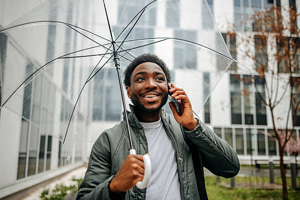 istock Man going to work walking outside on rainy day while talking on mobile phone 2207145450