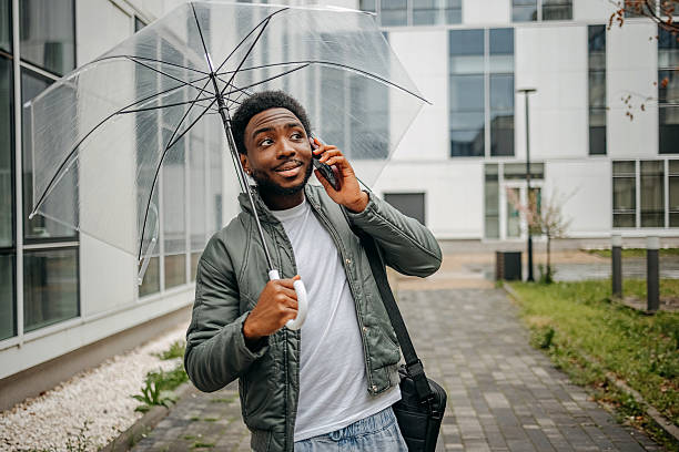 istock Man going to work walking outside on rainy day while talking on mobile phone 2207145464