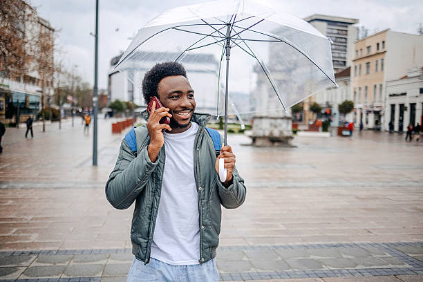 istock Man going to work walking outside on rainy day while talking on mobile phone 2207145524