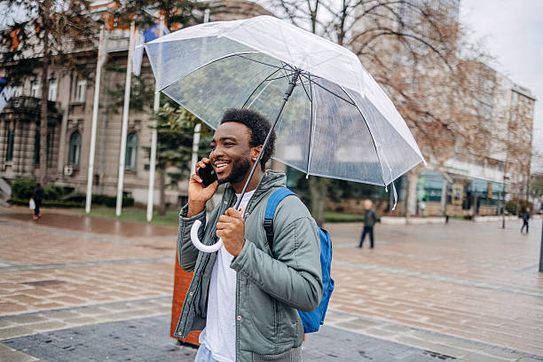 istock Man going to work walking outside on rainy day while talking on mobile phone 2207145526