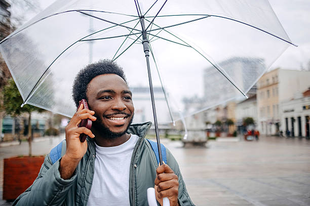 istock Man going to work walking outside on rainy day while talking on mobile phone 2207145528