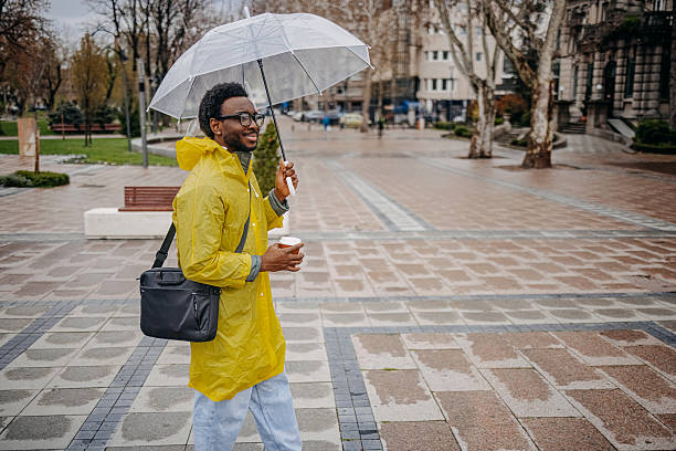 istock Man going to work walking outside on rainy day holding umbrella 2207145574
