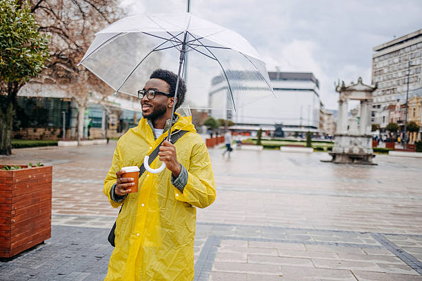 istock Man going to work walking outside on rainy day holding umbrella 2207145575