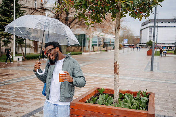 Man going to work walking outside on rainy day while talking on mobile phone