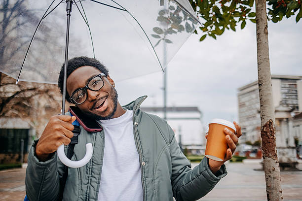 istock Man going to work walking outside on rainy day while talking on mobile phone 2207145640
