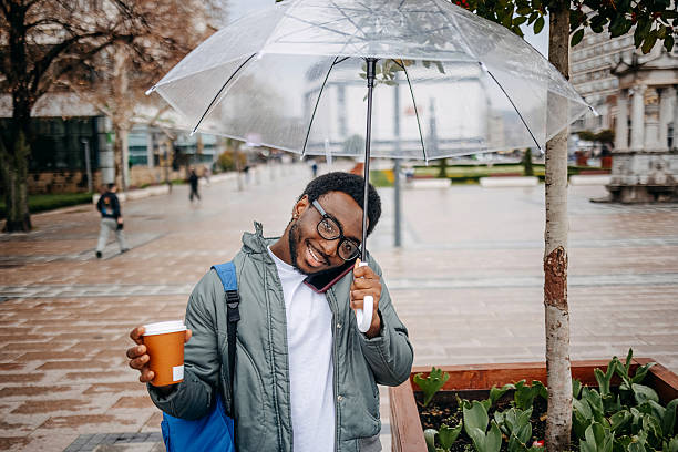 istock Man going to work walking outside on rainy day while talking on mobile phone 2207145643