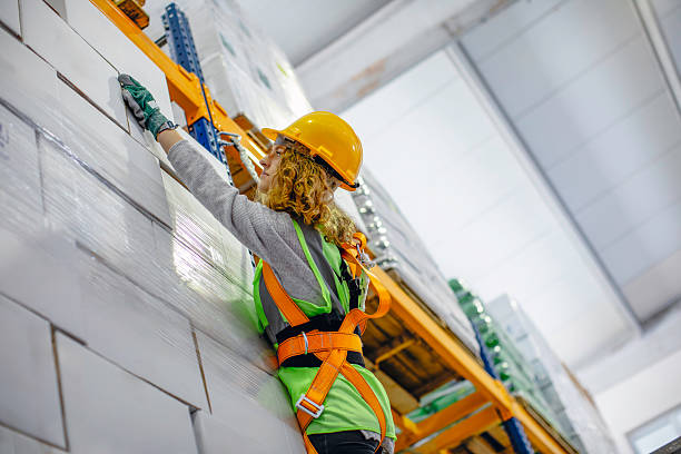 istock Warehouse worker hanging on a climbing rope while organizing boxes on high shelf. 2207151230