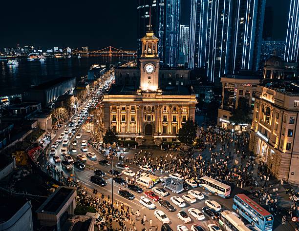 Night view of a bustling city intersection with illuminated buildings and a clock tower, showcasing urban life and city lights.
