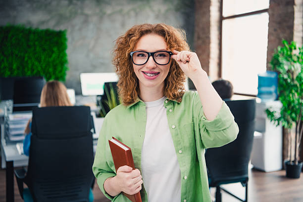 istock Cheerful Woman in Casual Attire Holding Notebook in Modern Shared Office Workspace Showing Friendly and Productive Atmosphere 2207153410