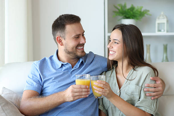 istock Happy couple toasting with orange juice glasses 2207154049