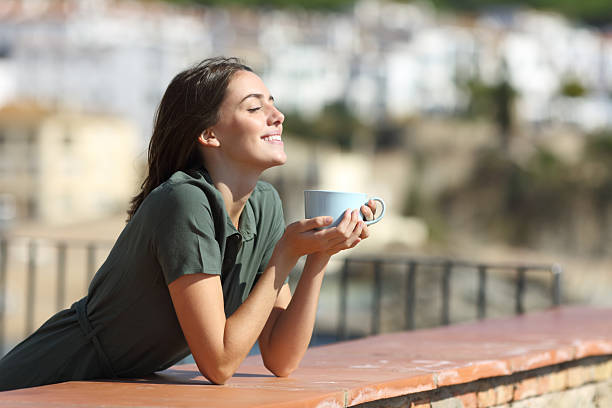 Woman in a terrace sunbathing drinking coffee stock photo