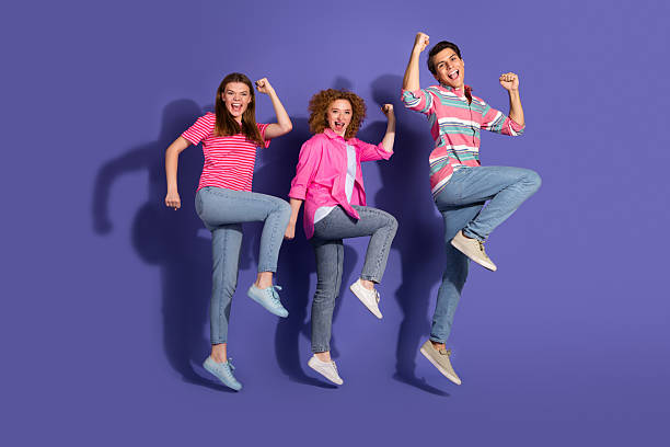 istock Joyful group of three students jumping together against a violet background, expressing happiness and youthful energy 2207154175