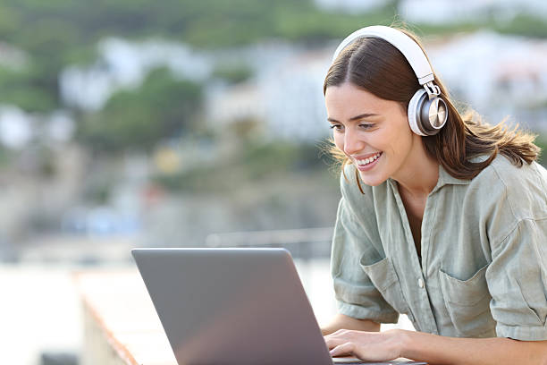 istock Happy woman wearing headphone using laptop on the beach 2207154201