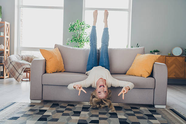 istock Smiling blonde woman relaxing upside down on a sofa in a modern home interior with bright natural light in a cozy and stylish atmosphere 2207155423