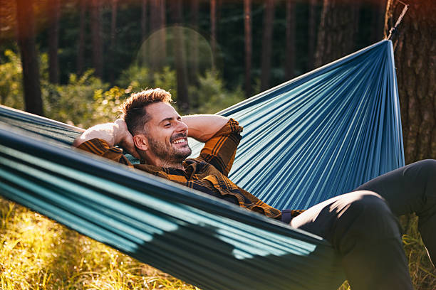 istock Man camping in forest resting in hammock enjoying vacation in nature 2207155842