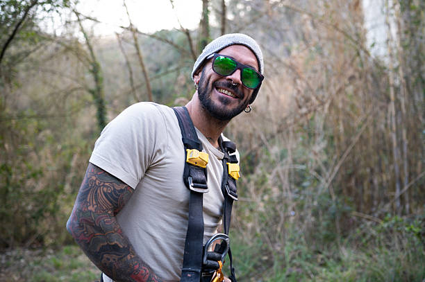 Portrait of a smiling worker wearing a safety harness and sunglasses, ready for work in a bridge