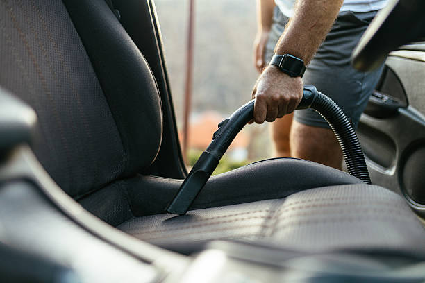 istock Man Vacuuming Car Seat Interior with Vacuum Cleaner in Sunlight 2207160467