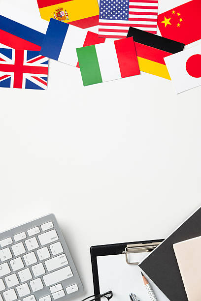 istock Colorful international flags arranged above an office workspace with a keyboard, clipboard, and stationery, symbolizing global business, education, travel, and cultural diversity 2207161295