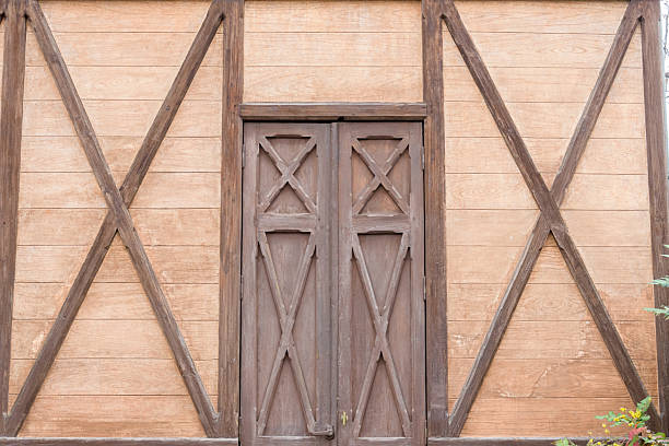 Close-up of a rustic wooden door with decorative truss framing. The construction features wooden planks and a visible truss structure, creating a vintage or country-style architectural detail.
