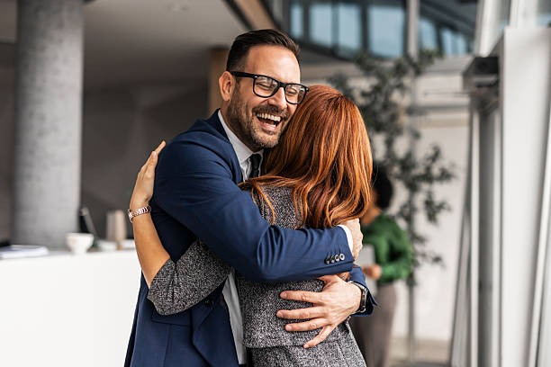 istock Happy Colleagues Hugging in Office Setting with Bright Atmosphere 2207162254