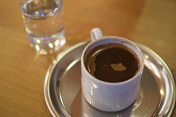 A steaming Turkish coffee served in a traditional floral cup on a checkered tablecloth. Perfect for cultural, culinary, or cozy home-themed projects.