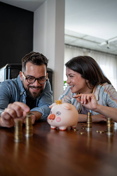 istock Young couple saving money at home using piggy bank 2207171463