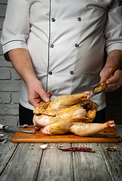 istock A skilled chef expertly seasons a whole chicken on a wooden cutting board. The rustic kitchen backdrop enhances the culinary atmosphere, showcasing culinary art in progress 2207173177