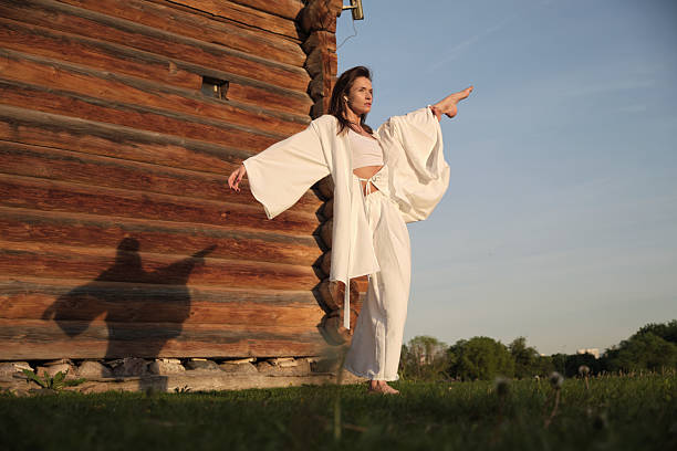 istock A dancer in white robes gracefully moves beside a log cabin under the setting sun. The image highlights the serene and artistic interaction between human movement and natural surroundings. 2207174237