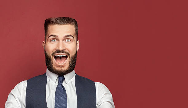 istock Young man with a surprised happy expression won on red studio background. Human facial emotions and expression concept. 2207175295
