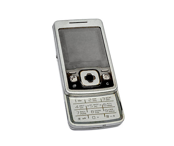 Old flip mobile phone with physical keypad on white background for nostalgia