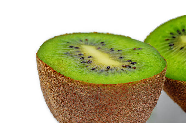 Cut kiwi halves showing black seeds on white background for tropical fruit display