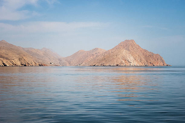 The dramatic landscape of Oman, with its rugged mountains and ethereal light, captured from the tranquil waters below.