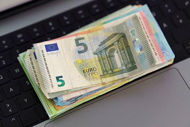 Euro cash on laptop keyboard – symbolic image for digital finance, online payments or economic control in Europe