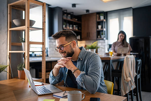 istock Young man working from home and smiling at laptop 2207187469