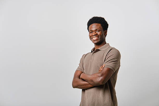 istock Young black man smiling with folded arms on white background 2207188716